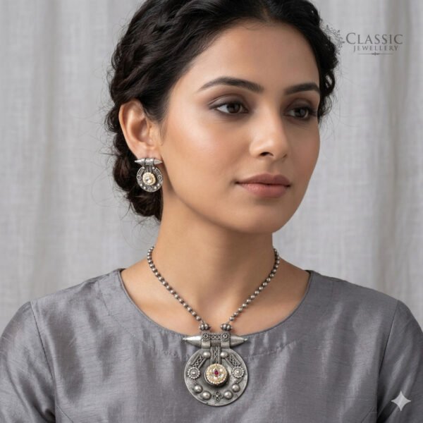 Model wear A handcrafted German silver pendant necklace and matching earrings featuring kundan stones, a central ruby, and intricate tribal engravings.