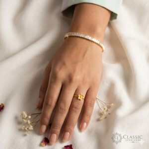 Model wear A delicate gold-plated tennis bracelet with square baguette crystal stones on a woman's wrist.