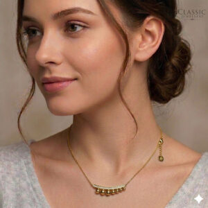 Model wear A fine gold chain necklace featuring a curved bar pendant pave-set with small round white crystals, from which five polished gold spheres of varying sizes are suspended.