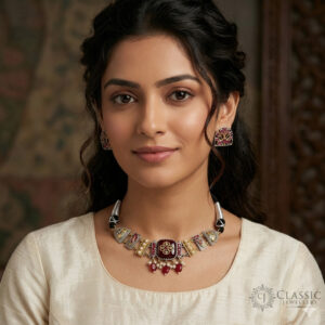 A detailed Indian heritage-style choker featuring deep ruby stones, intricate gold and silver metalwork, and delicate pearl drops, shown on a model.