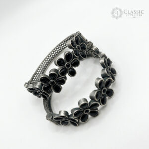 A pair of German silver bangles with black floral stone settings.
