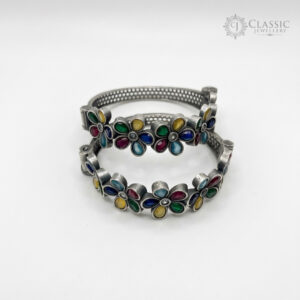 A pair of German silver bangles with colorful floral stone settings.