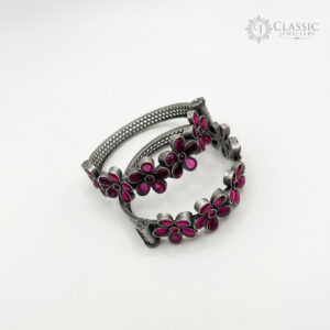 A pair of German silver bangles with pink floral stone settings.