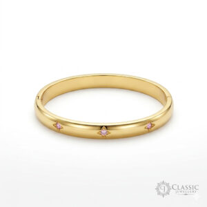 A sleek, polished gold-plated hinge kada featuring three inset starburst engravings with central pink cubic zirconia stones.