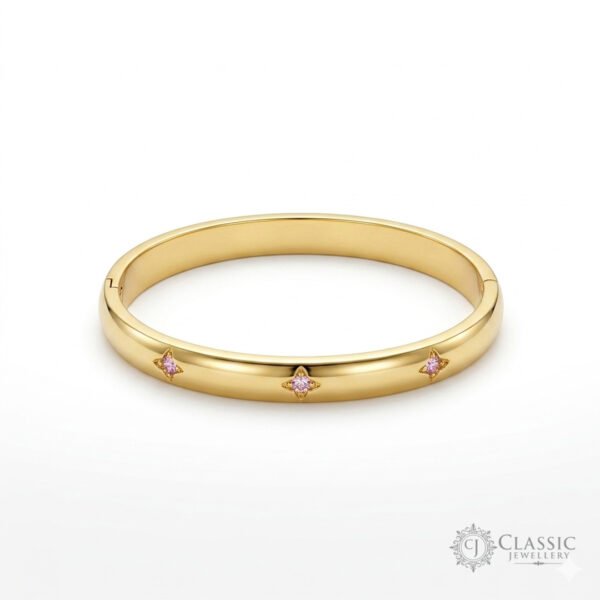 A sleek, polished gold-plated hinge kada featuring three inset starburst engravings with central pink cubic zirconia stones.