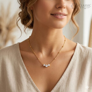 Model wearing a dainty gold chain with a three-stone triangular diamond pendant by Classicjewellery