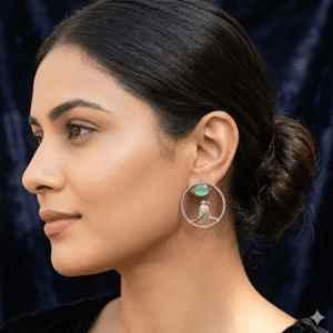 Woman wearing oxidised silver hoop earrings featuring bird motif and Green stone detailing.
