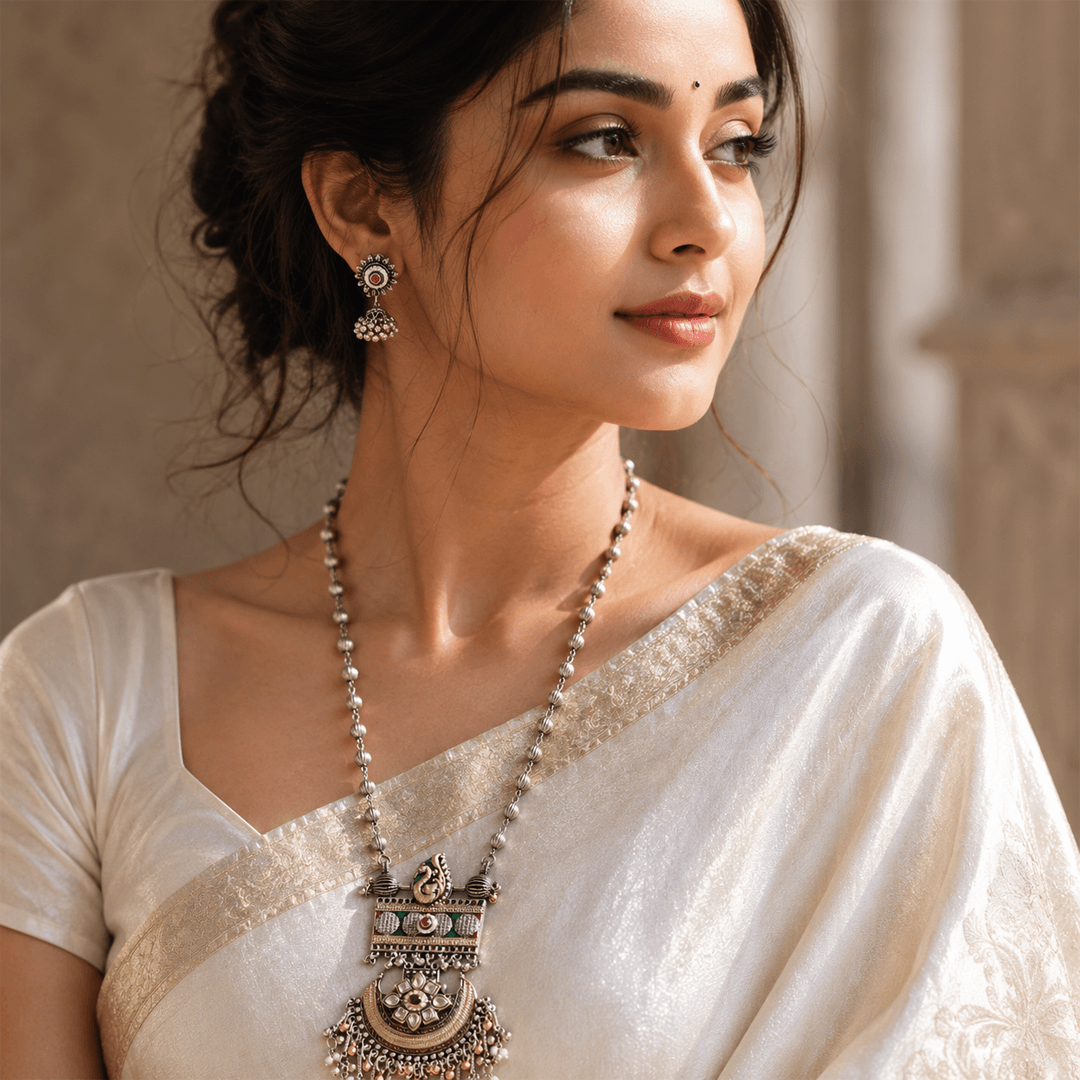 Beautiful woman wearing traditional oxidized silver temple necklace with matching earrings in white saree