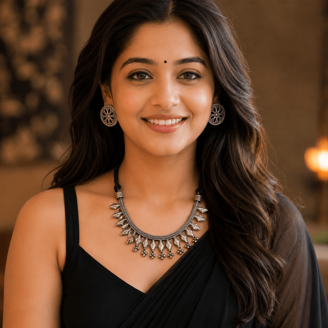 A model wearing a Kreezo oxidized German silver necklace set featuring diamond-shaped geometric pendants with small bead droplets and matching circular floral-patterned stud earrings.
