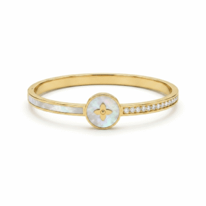 A slim, polished gold hinged kada featuring a central round medallion with an iridescent mother of pearl inlay and a gold four-petal floral monogram, flanked by a smooth mother-of-pearl band on one shoulder and a row of pave diamonds on the other.