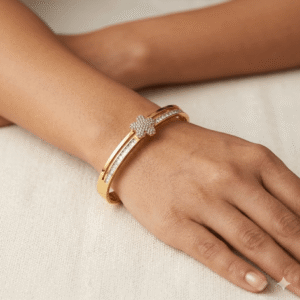 Model wear A polished gold split-band bangle bracelet featuring a central five-petal flower motif encrusted with micro-pave diamonds and diamond-lined shoulders