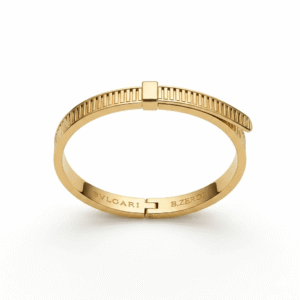 A polished yellow gold hinged bangle bracelet featuring a structured architectural ribbed pattern along the band, an asymmetric overlapping top closure with a central square clasp accent, and inner brand engravings on a white background.