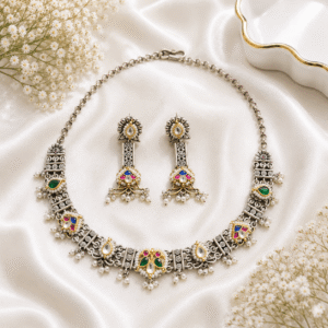 Traditional German silver necklace set with multicolor stones, pearl detailing, and matching statement earrings on white satin background.