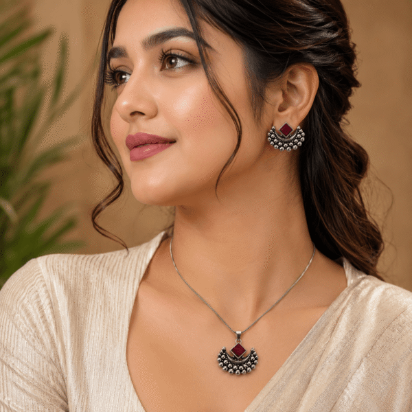 Woman wearing oxidised silver necklace pendant set with ruby red stone and matching earrings