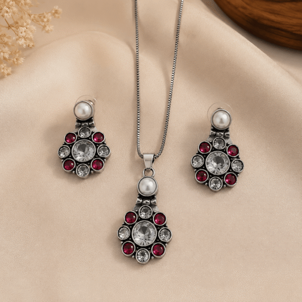 Woman wearing oxidised silver pendant necklace set with pearl, ruby stones, and matching earrings