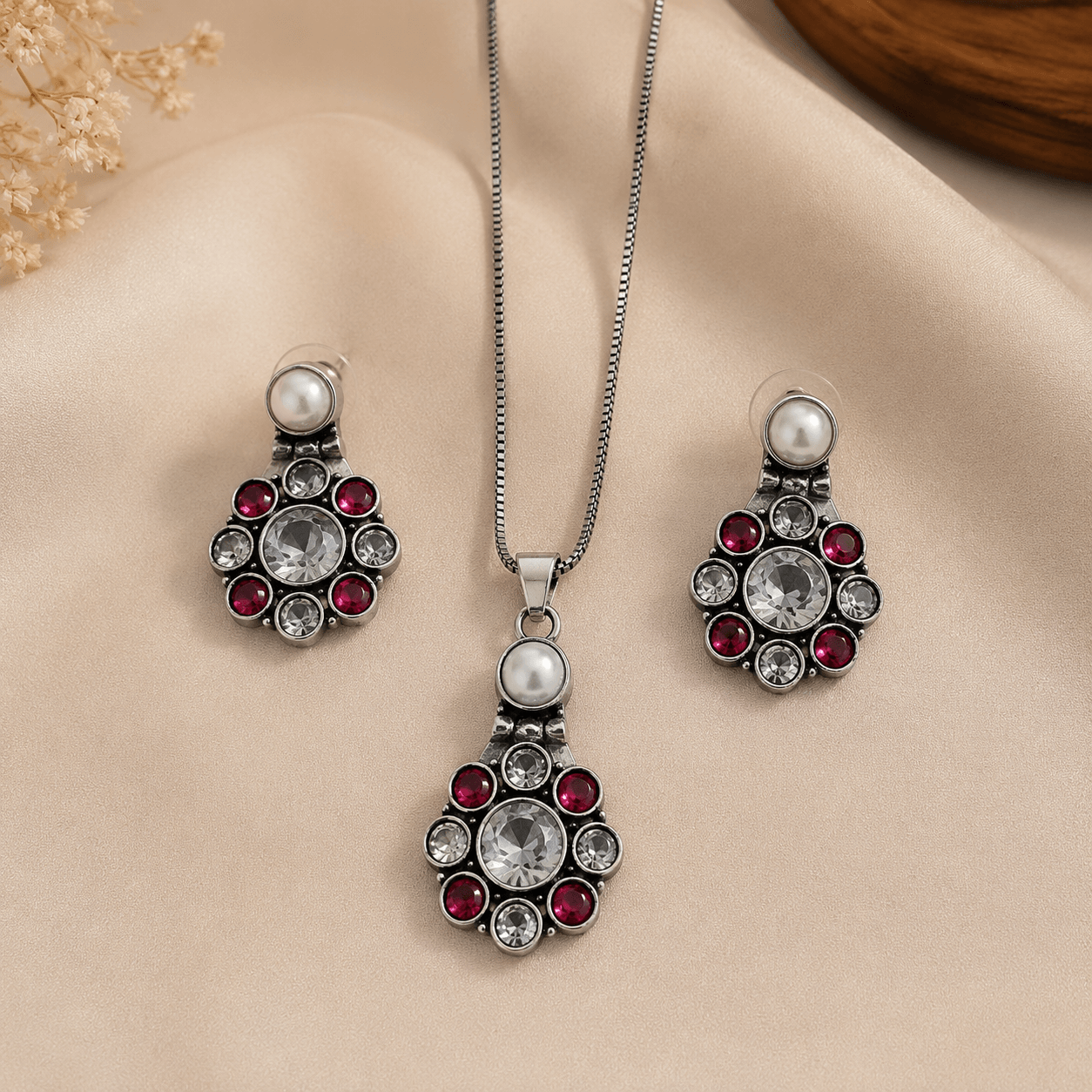 Woman wearing oxidised silver pendant necklace set with pearl, ruby stones, and matching earrings