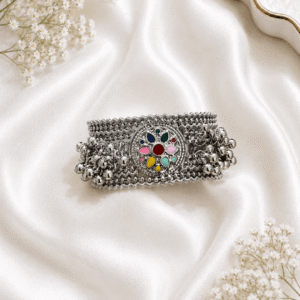 Oxidized silver kada bracelet with multicolor floral center motif and ghungroo bead detailing on white satin background