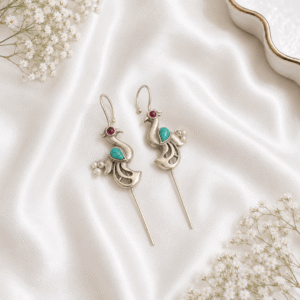A pair of intricate, artisan-crafted peacock-shaped ear cuffs made of German silver