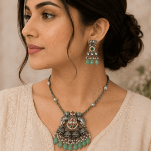 Woman wearing an antique silver elephant pendant necklace with matching elephant earrings and mint green bead drops in a premium ethnic jewelry photoshoot.