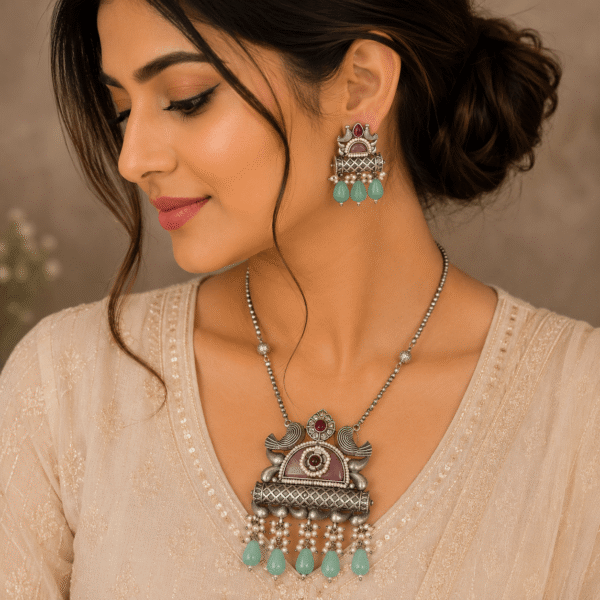 Woman wearing an antique silver temple pendant necklace with matching earrings featuring pearl clusters and mint green teardrop beads in a premium ethnic jewelry photoshoot.