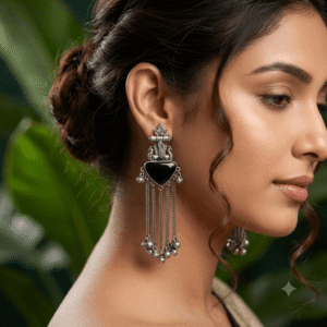 Close-up of a woman wearing premium German silver long tassel earrings featuring a black heart-shaped stone, antique detailing, and ghungroo accents.