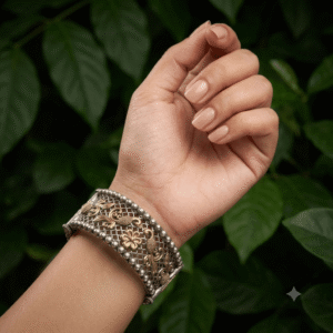Close-up of a woman wearing a premium German silver dual-tone floral cuff kada with antique detailing and openwork design.