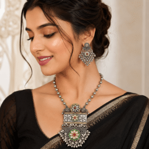 Woman wearing a premium oxidized silver necklace set featuring a floral pendant with ghungroo tassels and matching oxidized earrings.