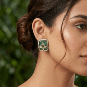 Close-up of a woman wearing premium oxidized German silver square stud earrings featuring a green stone and floral motif.