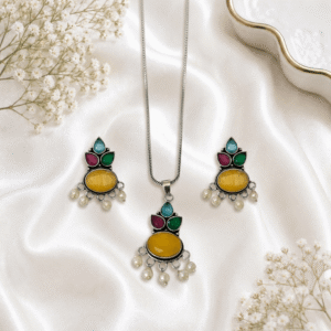 A young woman wearing a traditional oxidized silver necklace and earring set featuring multi stones and pearl hangings on a black kurti.