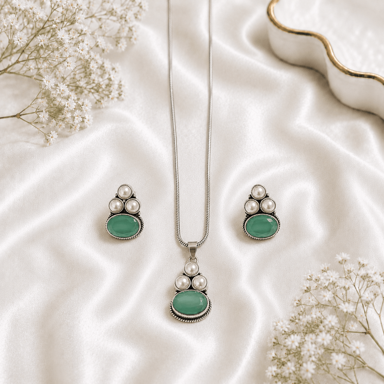 A young woman wearing a traditional oxidized silver necklace and earring set featuring green stones and pearl hangings on a black kurti.