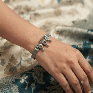 Woman wearing an oxidised silver adjustable kada bracelet with multicolor stone floral charms and traditional ethnic design.