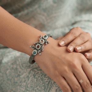 Woman wearing an oxidised silver adjustable kada bracelet with multicolor stone floral charms and traditional ethnic design.