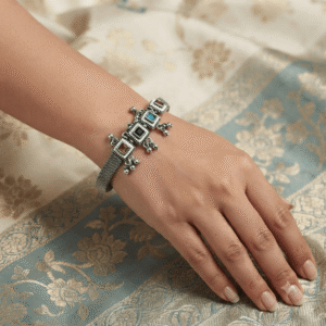 Woman wearing an oxidised silver adjustable kada bracelet with multicolor stone floral charms and traditional ethnic design.