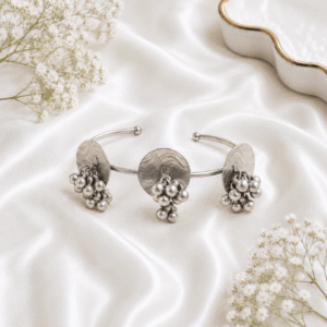 Oxidised silver kada bracelet with round disc design, dangling ghungroo beads and antique finish displayed on satin background.
