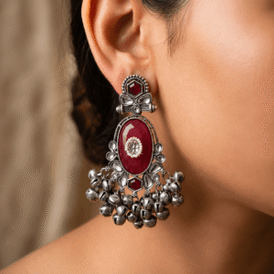 Oxidised silver earrings with ruby red stone, pearl detailing, floral design and dangling ghungroo beads worn on ear.
