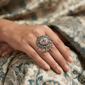 Premium close-up of a woman wearing an oxidized German silver floral statement ring with a pink stone and hanging ghungroo detailing.