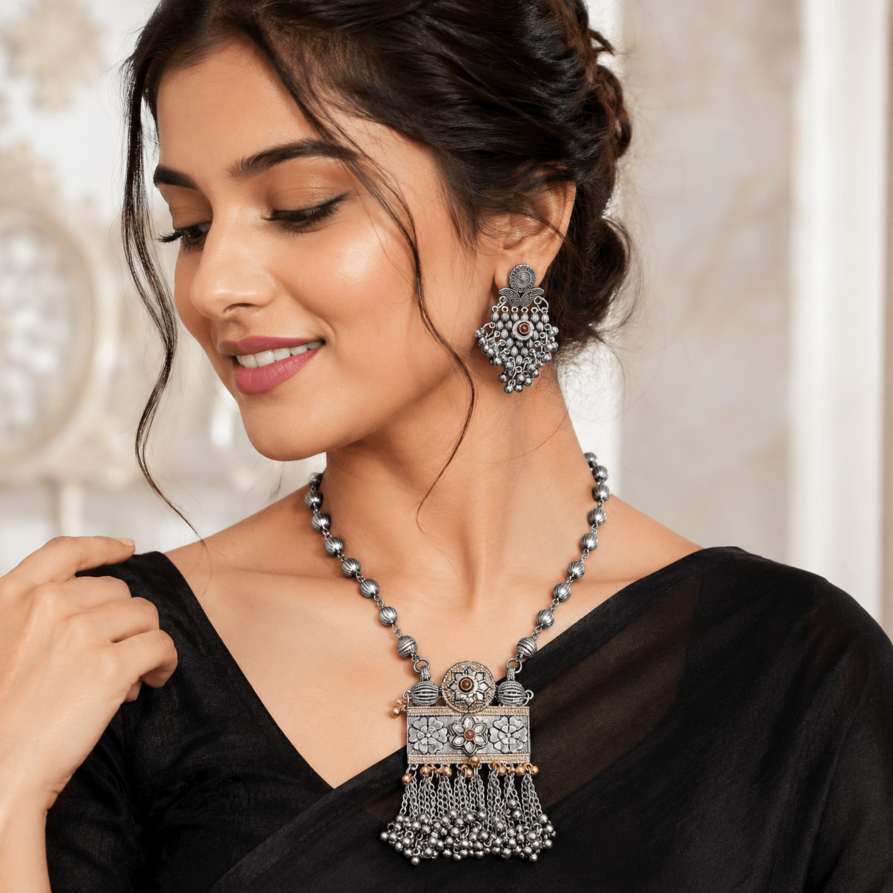 Woman wearing a premium oxidized silver necklace set featuring a floral pendant with ghungroo tassels and matching oxidized earrings.