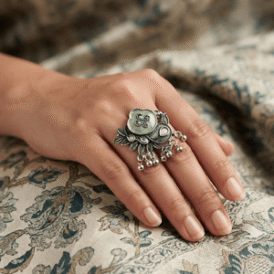 Close-up of a woman wearing a premium oxidized German silver floral statement ring featuring a green stone, pink accents, and ghungroo detailing.