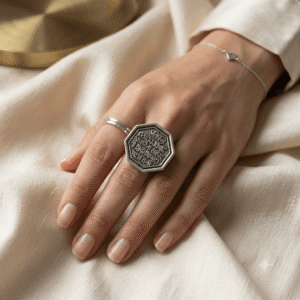 Woman's hand wearing a vintage silver octagonal ring with intricate Devanagari script engraving.