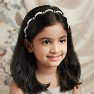 Young girl wearing a white pearl beaded hair band, elegant headband for girls suitable for parties and special occasions.