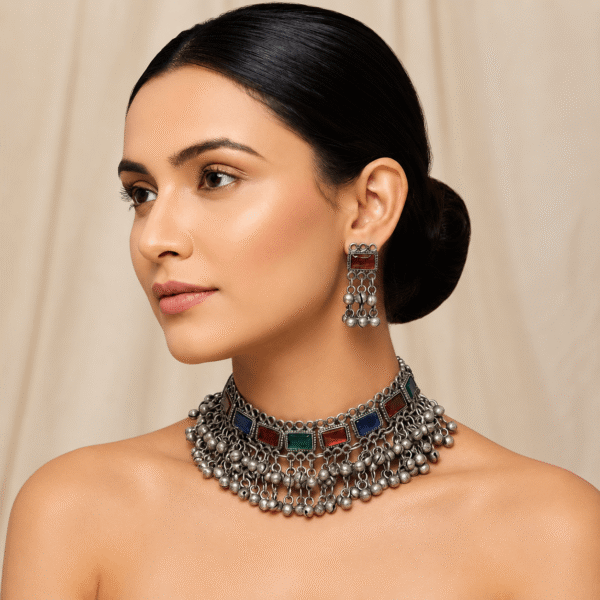 Model wearing Kreezo handcrafted German silver choker necklace featuring rectangular red, green, and blue stones with ghungroo bead drops and matching earrings.