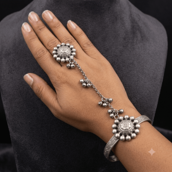 Model wearing a Kreezo oxidized silver hathphool featuring interconnected floral sunflower motifs, a wrist cuff, and a finger ring linked by a delicate beaded chain against a neutral background