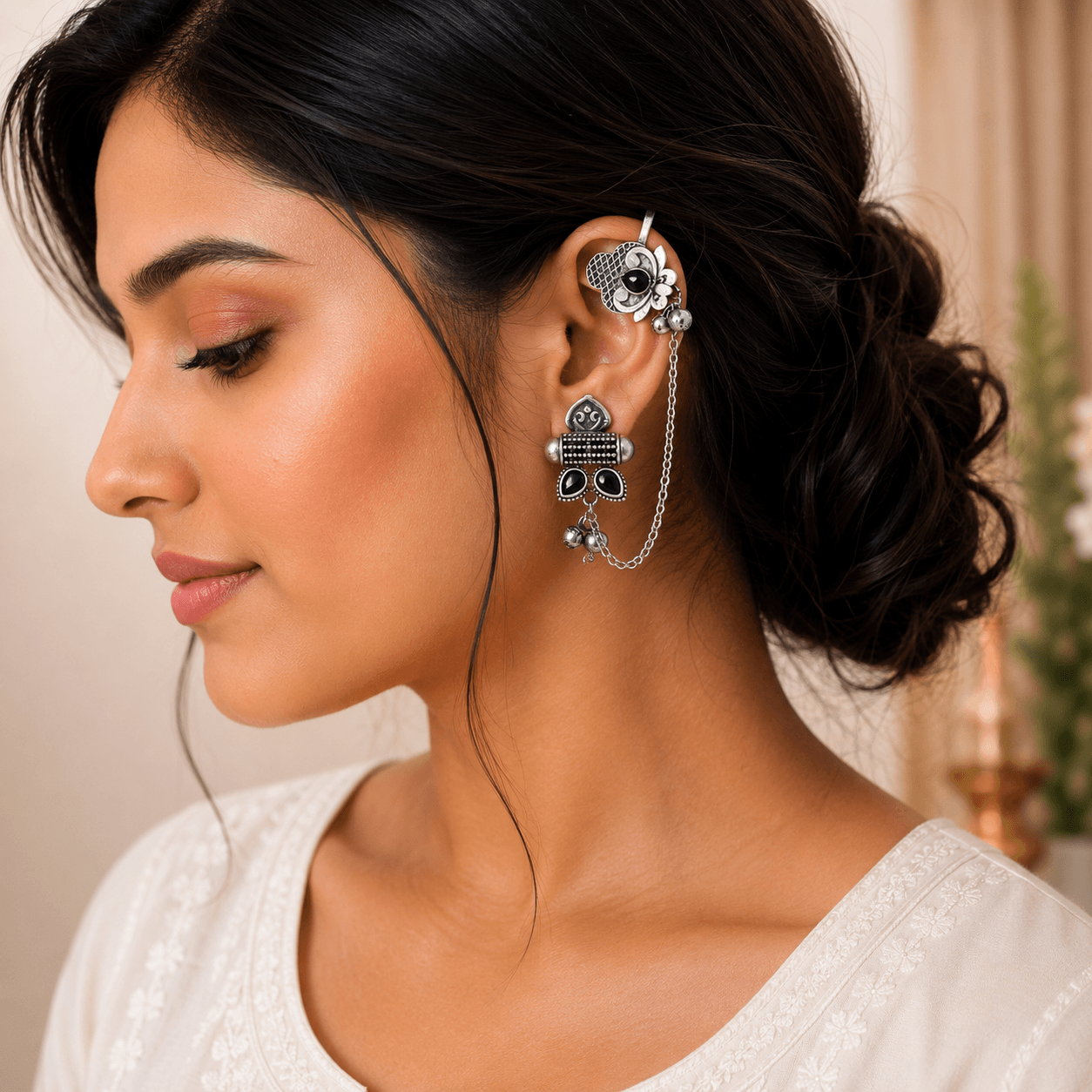 Woman wearing premium German silver ear cuff earrings with black stones, chain, and ghungroo detailing on the right ear.