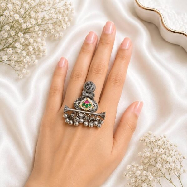 Hand wearing an oxidized German silver ethnic statement ring featuring colorful stone accents and hanging silver ghungroo bells from Kreezo