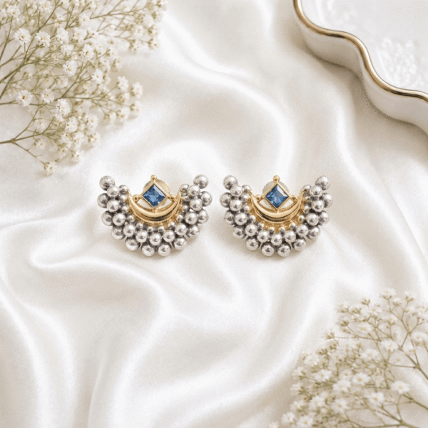 A pair of Kreezo German silver crescent-shaped stud earrings featuring clustered silver beads, a gold-tone crescent motif, and a central square blue stone.