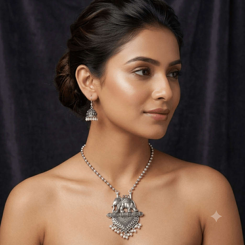 Model wearing a Kreezo oxidized silver beaded chain necklace with an intricate elephant pendant and matching pearl-beaded jhumka earrings against a dark background