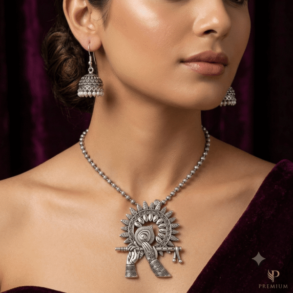 Model wearing a Kreezo oxidized silver beaded chain necklace with an intricate Lord Krishna flute and peacock motif pendant, styled with matching pearl-beaded jhumka earrings