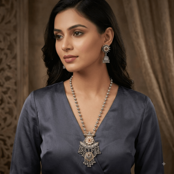Model wearing a Kreezo oxidized silver beaded long chain necklace with an elaborate statement pendant featuring floral motifs, stonework, and hanging bead chains, accompanied by matching jhumka earrings against a dark background