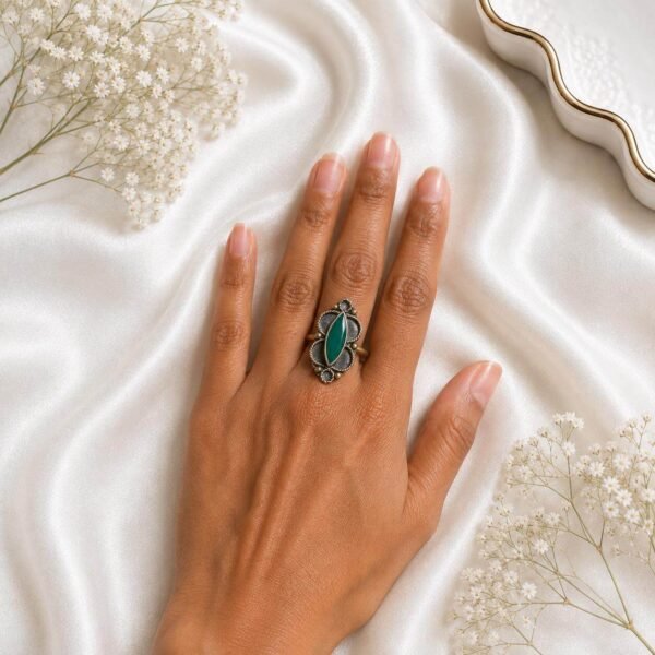 silver statement ring with a maroon oval stone and intricate floral detailing